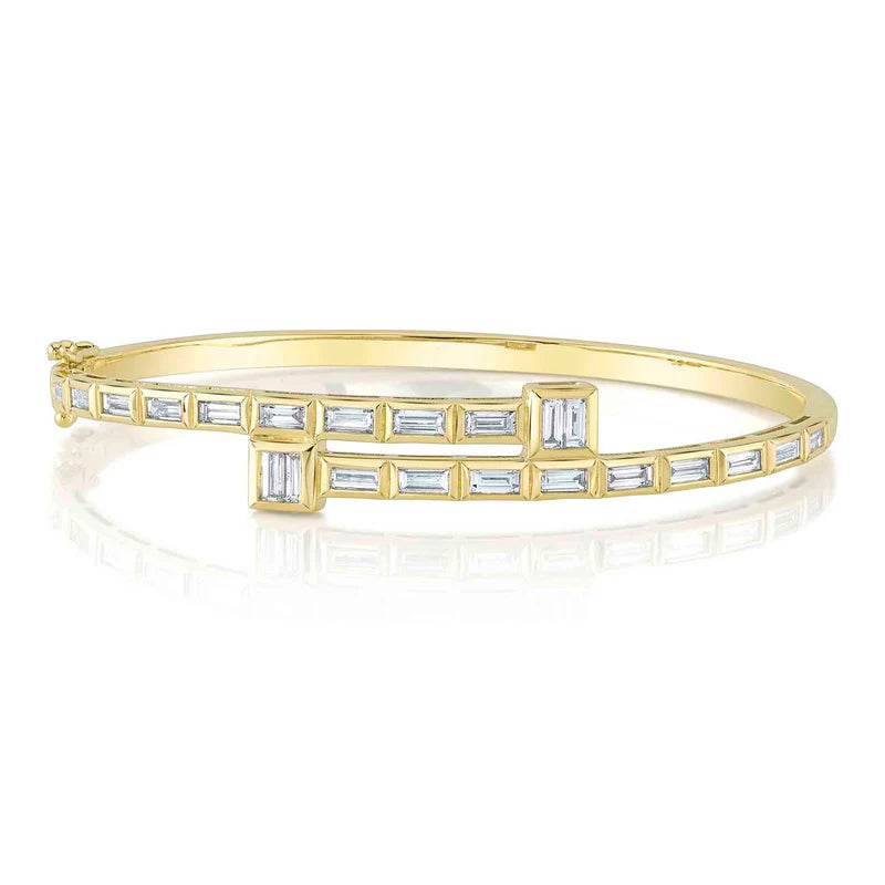 A gold bangle bracelet with a series of baguette-cut diamonds on the bezel.