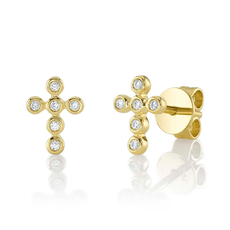 A pair of 14k gold bezel cross stud earrings with diamond details.