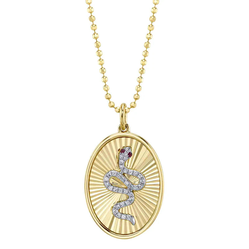 A gold-colored pendant necklace featuring a faceted design with a snake motif, adorned with ruby and diamond accents.